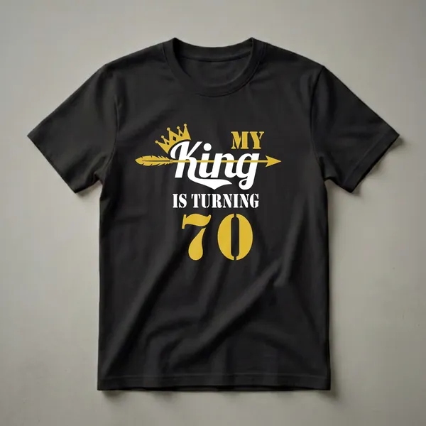 Black t-shirt with gold and white text that reads 'MY King IS TURNING 70', featuring a gold crown and a gold arrow.