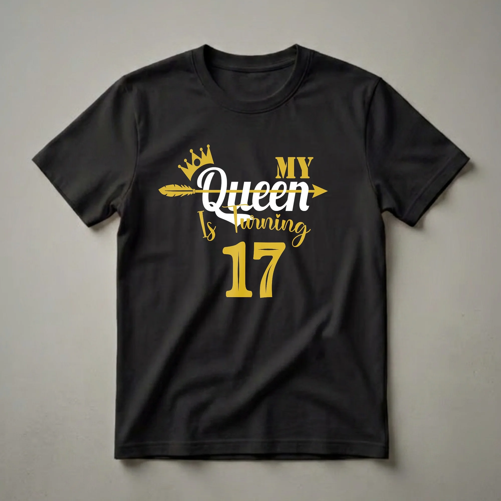 Black t-shirt with gold and white text that reads 'My Queen Is Turning 17' with a gold crown and an arrow graphic.