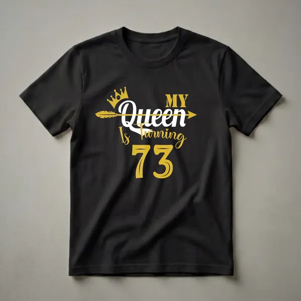 Black t-shirt with gold and white text that reads 'My Queen Is Turning 73' with a gold crown and arrow graphic.