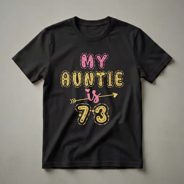 Black t-shirt with "MY AUNTIE is 73" written in glittery pink and gold bubble letters, adorned with hearts, stars, and an arrow.