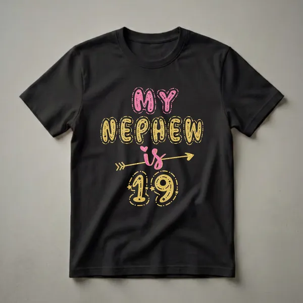 Black t-shirt with 'MY NEPHEW is 19' text graphic in pink and gold glitter texture, featuring hearts, stars, and an arrow.