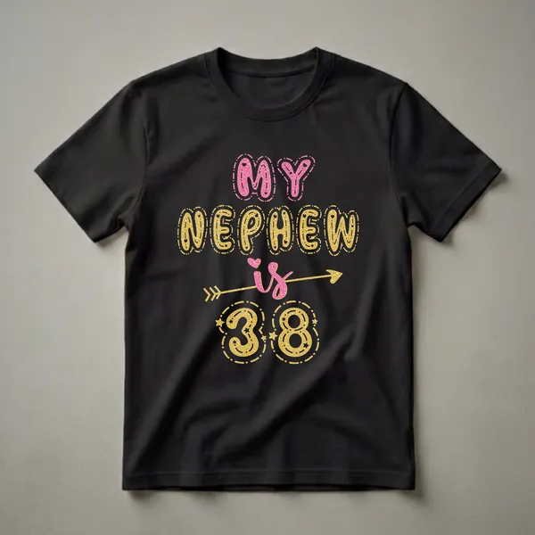Black t-shirt with "MY NEPHEW is 38" in bubbly, glittery pink and gold lettering, accented with hearts, stars, and dashed outlines.