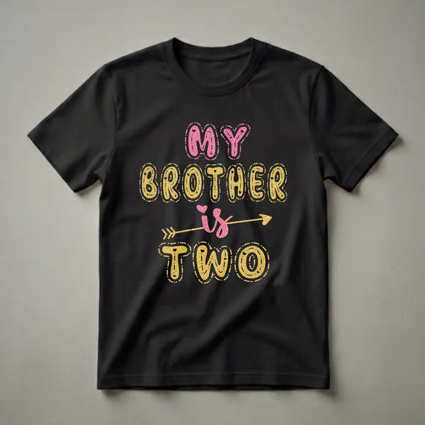 Black t-shirt with "MY BROTHER is TWO" text graphic in glittery pink and gold bubble letters, with a gold arrow through the word 'is'.