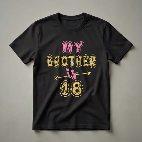 Black t-shirt with the text 'MY BROTHER is 18' in pink and gold glitter effect font, with stars and an arrow graphic.