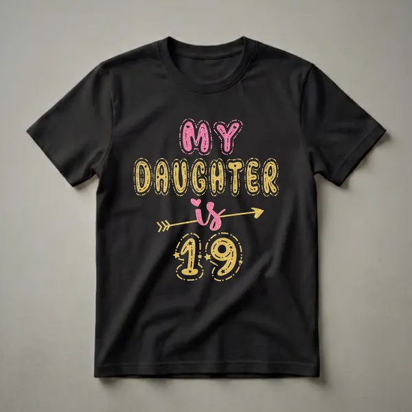 Black t-shirt with "MY DAUGHTER is 19" in large pink and gold glitter bubble letters, with stars and an arrow design.