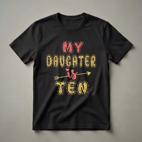 Black t-shirt with the text 'MY DAUGHTER is TEN' in red and gold glitter effect lettering, with an arrow through 'is'.