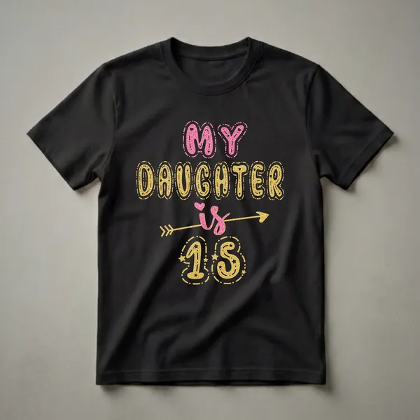 Black t-shirt with glittery pink and gold text that reads "MY DAUGHTER IS 15" with decorative elements like an arrow and stars.