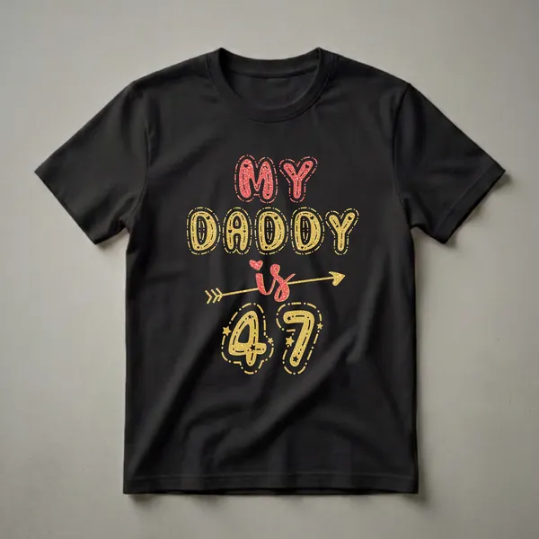 Black t-shirt with glitter-effect text that reads 'MY DADDY is 47' in red and gold, with decorative hearts and stars.