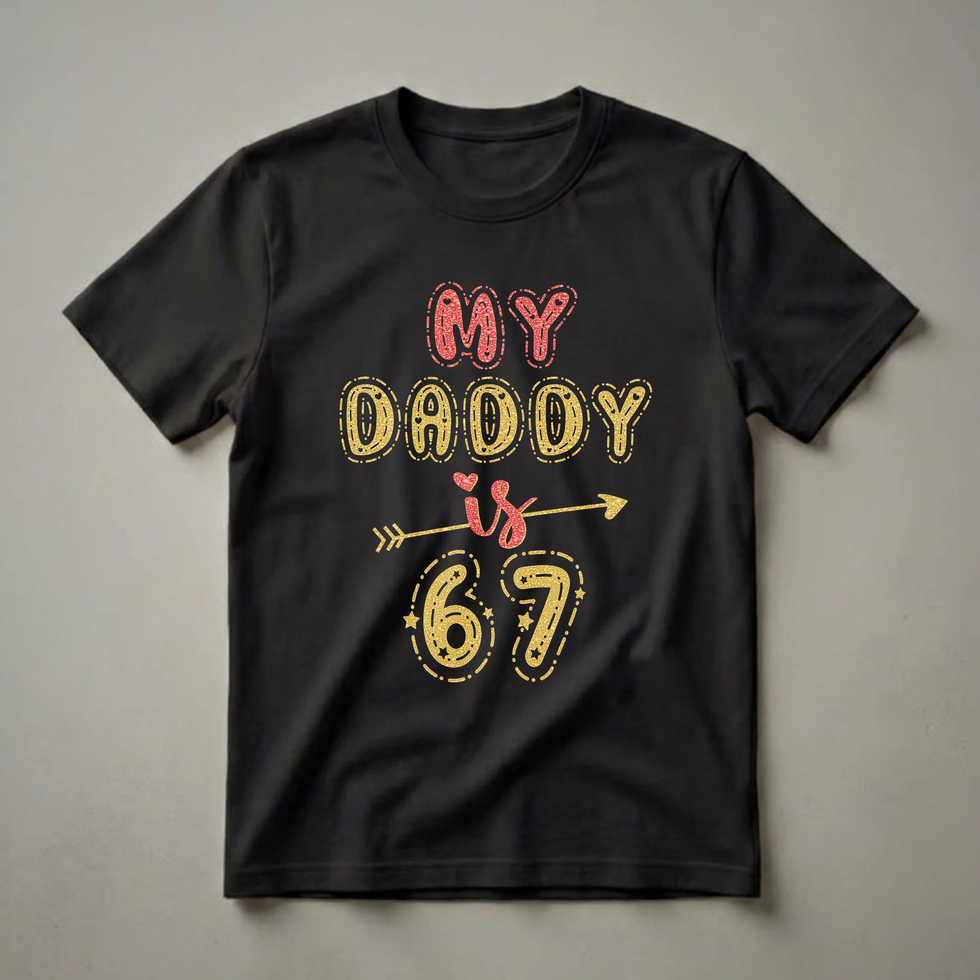 Black t-shirt with "MY DADDY is 67" in glittery red and gold bubble-style lettering, adorned with hearts, stars, and an arrow.