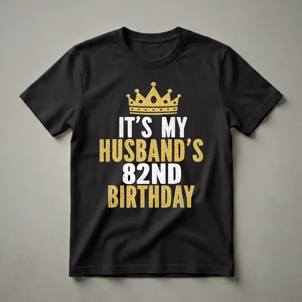 Black t-shirt with a gold glitter crown and white and gold glitter text that reads 'IT'S MY HUSBAND'S 82ND BIRTHDAY'.