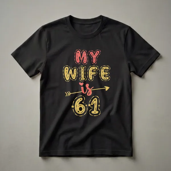 Black t-shirt with the text "MY WIFE is 61" in red and gold glitter effect lettering, with decorative arrows and stars.