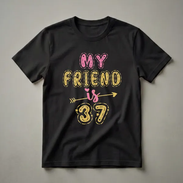 Black t-shirt with "MY FRIEND is 37" in glittery pink and gold bubble letters, accented with stars and an arrow.