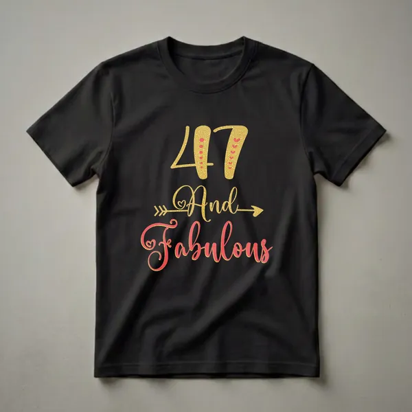 Black t-shirt with '47 And Fabulous' text graphic. The number 47 and 'And' are in gold glitter, while 'Fabulous' is in coral glitter with a gold outline. Decorative arrows flank 'And'.