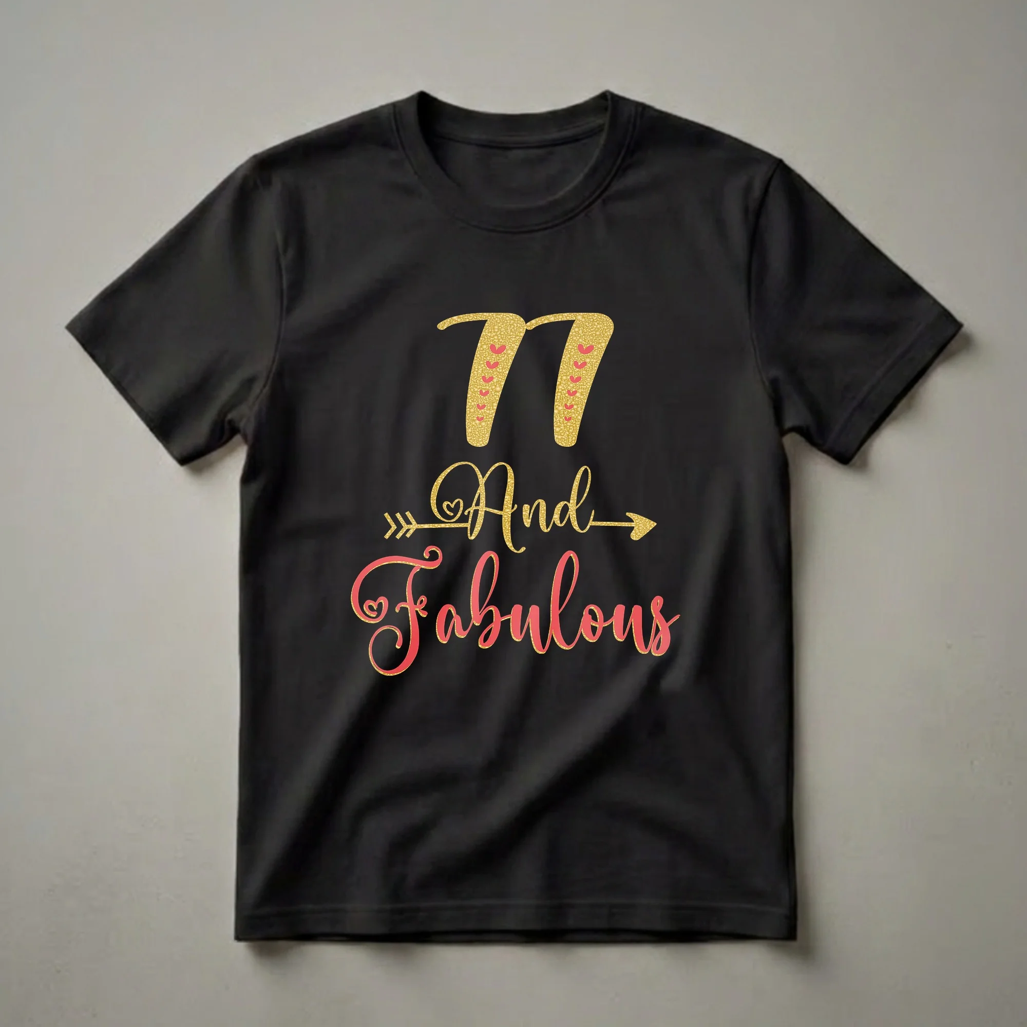 Black t-shirt with gold glitter '77' and coral and gold glitter 'And Fabulous' text graphic, accented with hearts and an arrow.