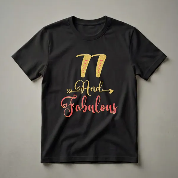 Black t-shirt with gold glitter '77' and coral and gold glitter 'And Fabulous' text graphic, accented with hearts and an arrow.