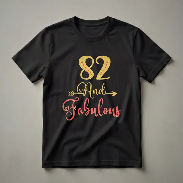 Black t-shirt with gold glitter '82' and red polka dots, followed by gold glitter 'And' with arrows, and coral glitter 'Fabulous' with gold outline.