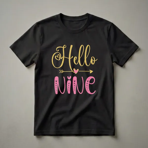 Black t-shirt with 'Hello Nine' text in glittery gold and pink fonts, featuring hearts and an arrow graphic.
