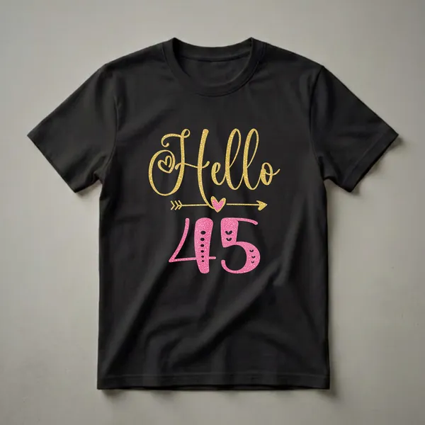 Black t-shirt with 'Hello 45' graphic. 'Hello' is in gold glitter script with a heart and arrow. '45' is in pink glitter texture with hearts.