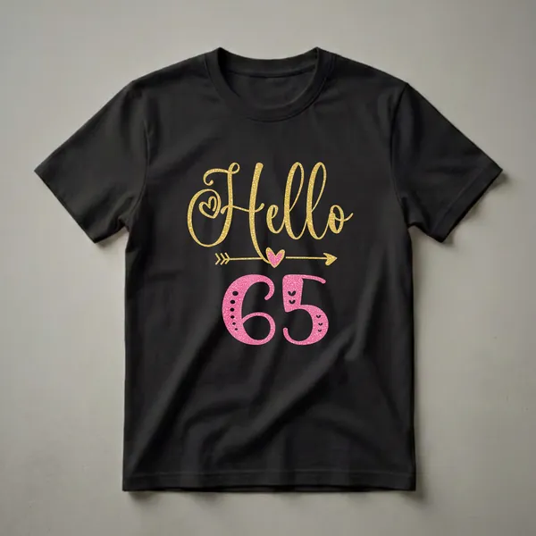 Black t-shirt with gold glitter script 'Hello' above pink textured numbers '65', with decorative hearts and arrows.