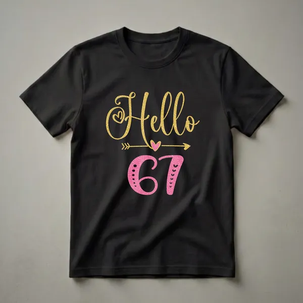 Black t-shirt with "Hello 67" graphic. "Hello" is in gold glitter script, and "67" is in pink glitter with decorative elements. A gold arrow passes through a pink heart.