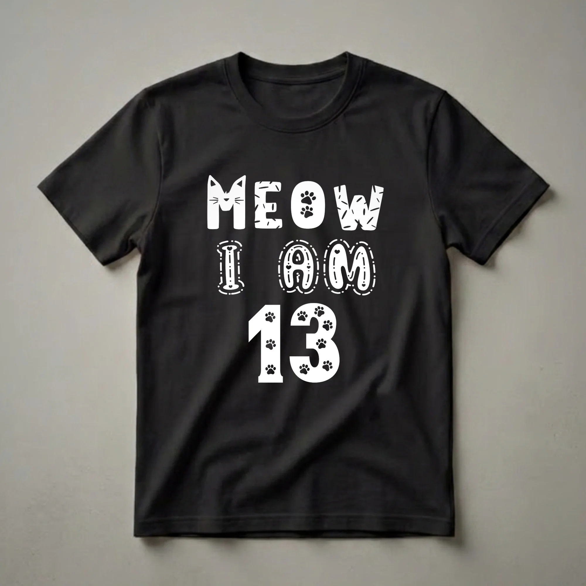 Black t-shirt with white text that reads 'MEOW I AM 13' in a playful font, featuring a cat face, paw prints, and decorative elements.