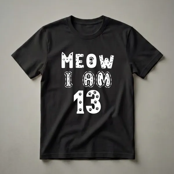 Black t-shirt with white text that reads 'MEOW I AM 13' in a playful font, featuring a cat face, paw prints, and decorative elements.