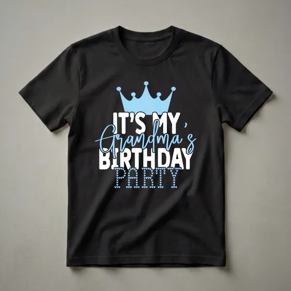 A black t-shirt graphic with a light blue crown and text that reads 'IT'S MY Grandma's BIRTHDAY PARTY', with the word 'PARTY' formed by small blue hearts.