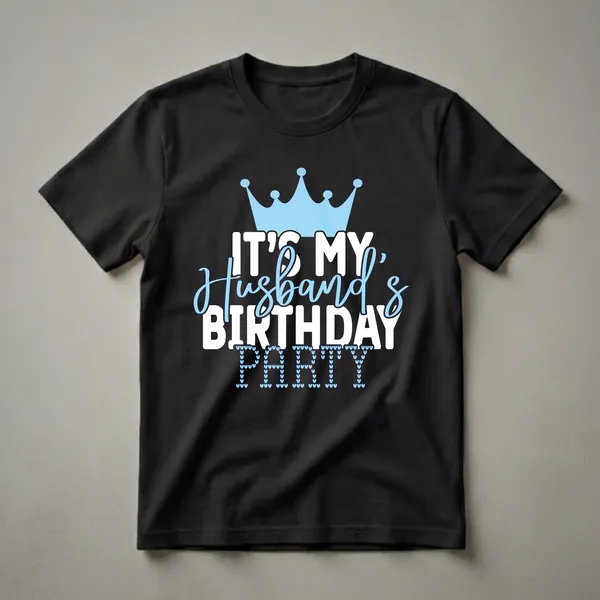 Black t-shirt with a light blue crown graphic and white text that reads 'IT'S MY Husband's BIRTHDAY PARTY', with the word 'PARTY' formed by small light blue hearts.