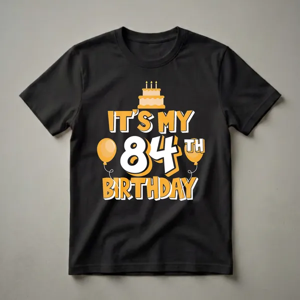 Black t-shirt with a graphic design that says 'IT'S MY 84TH BIRTHDAY' in orange and white, featuring a birthday cake with candles and two orange balloons.