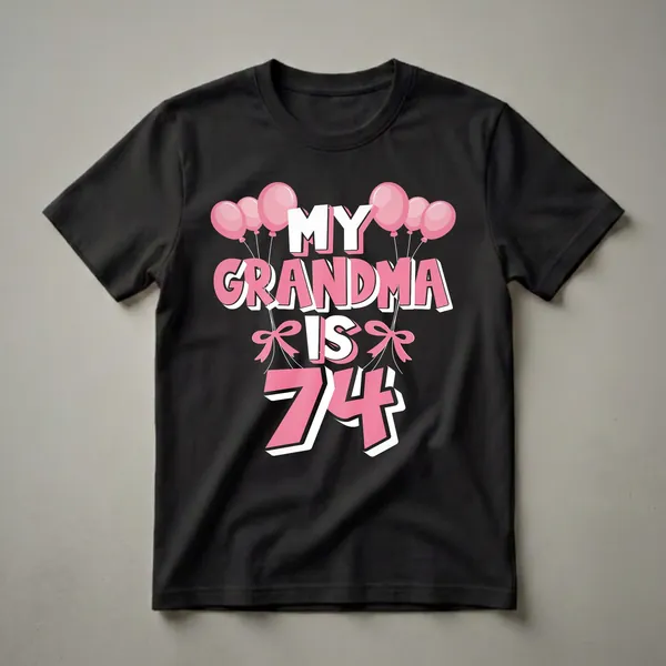 Black t-shirt with the text "MY GRANDMA IS 74" in large pink and white letters, adorned with pink balloons and bows.