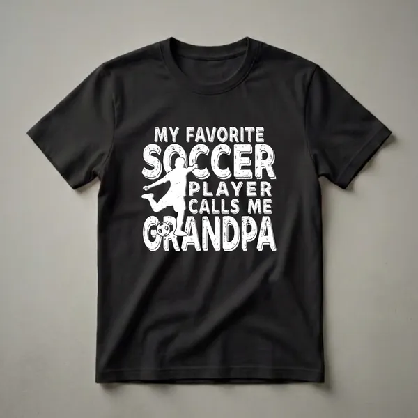 White distressed graphic t-shirt with the text "My Favorite Soccer Player Calls Me Grandpa" and an image of a soccer player kicking a ball.