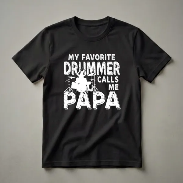 Black t-shirt with white distressed text that reads "My Favorite Drummer Calls Me Papa" and a graphic of a drummer playing a drum set.