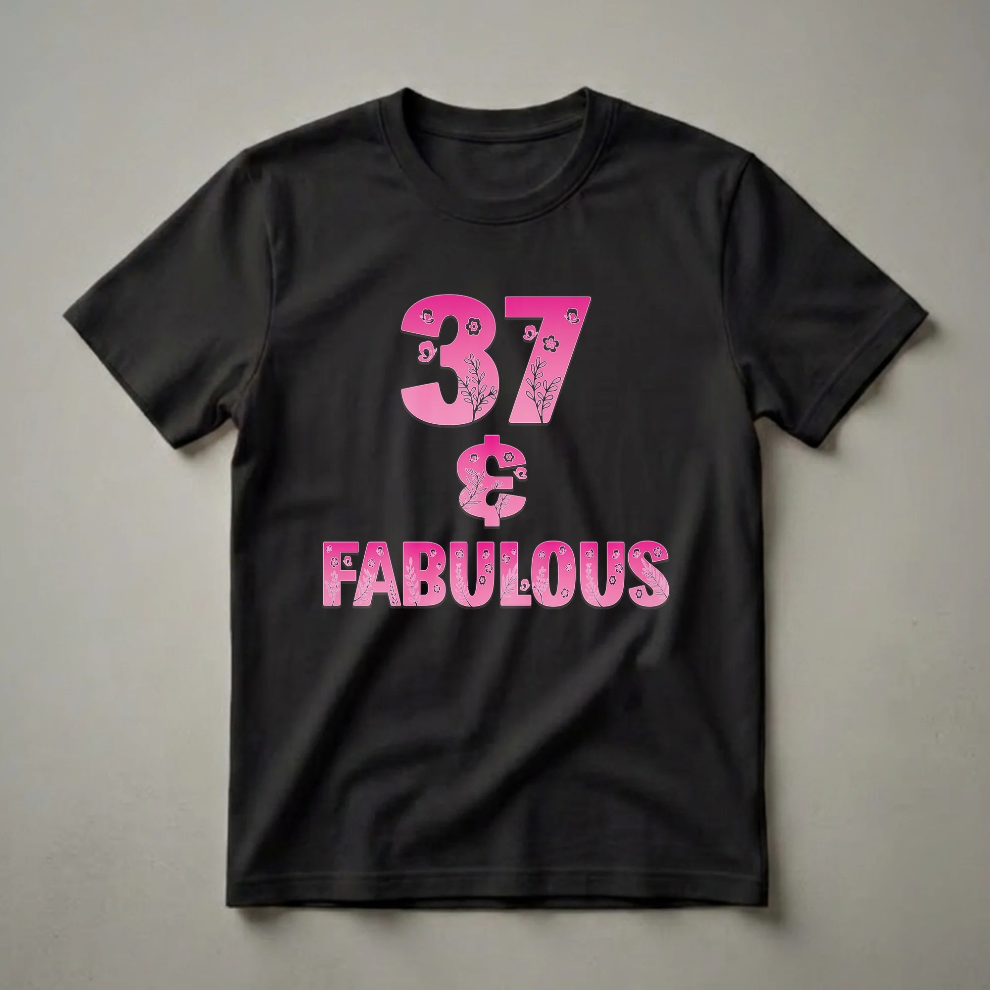 Pink graphic t-shirt with '37 & Fabulous' text, decorated with floral patterns and butterflies, on a black background.