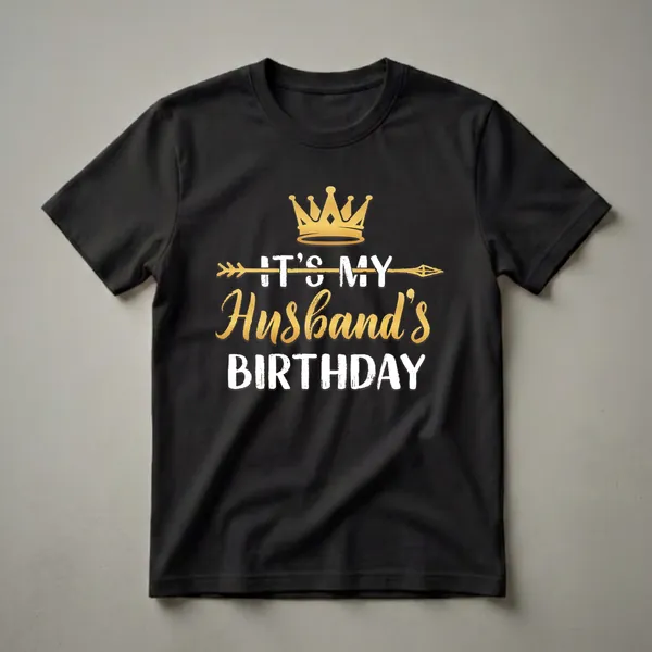 Black t-shirt with a golden crown graphic above the text 'IT'S MY HUSBAND'S BIRTHDAY' in white and gold fonts, with a golden arrow graphic.