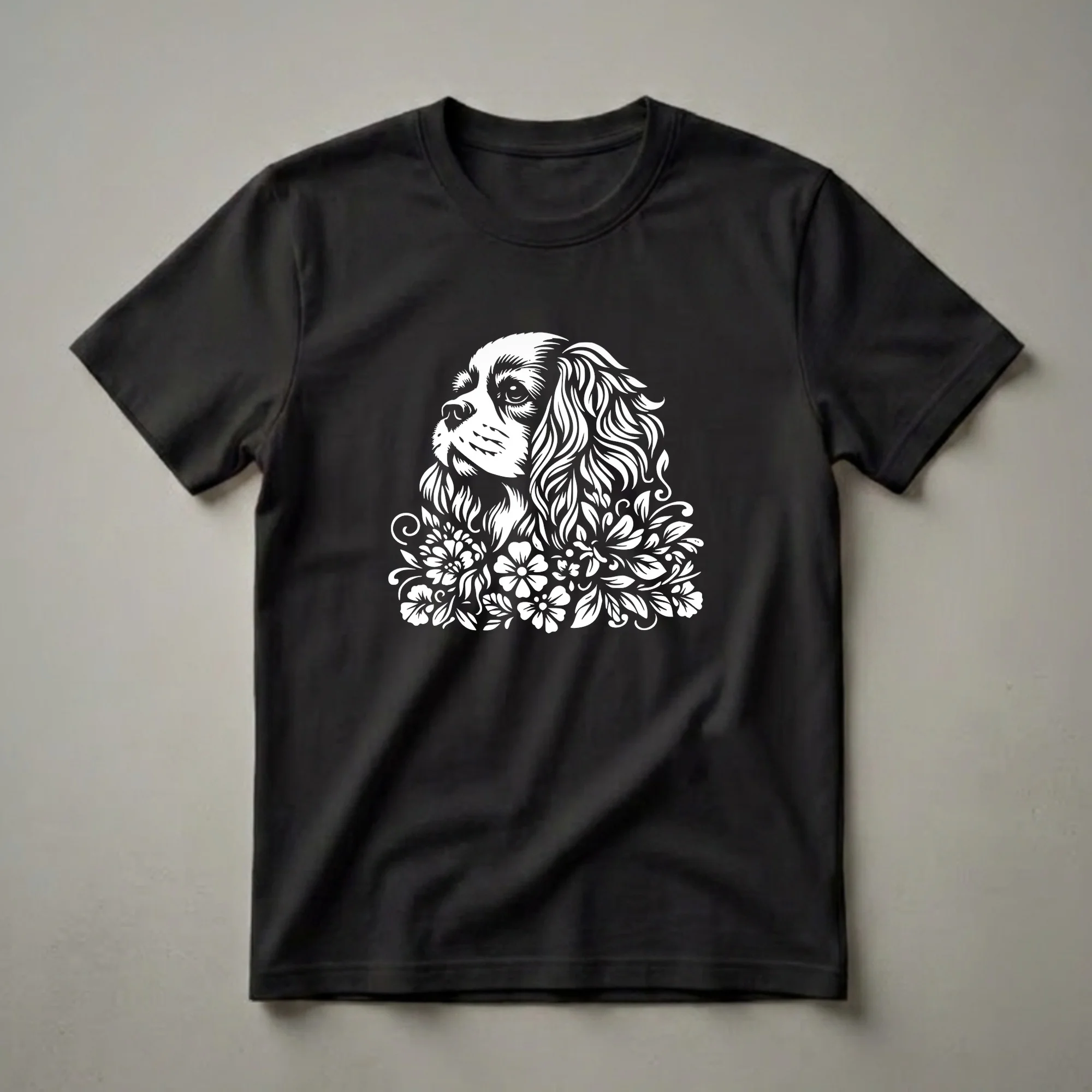 White graphic of a Cavalier King Charles Spaniel's head merging into a floral design, presented on a black t-shirt.