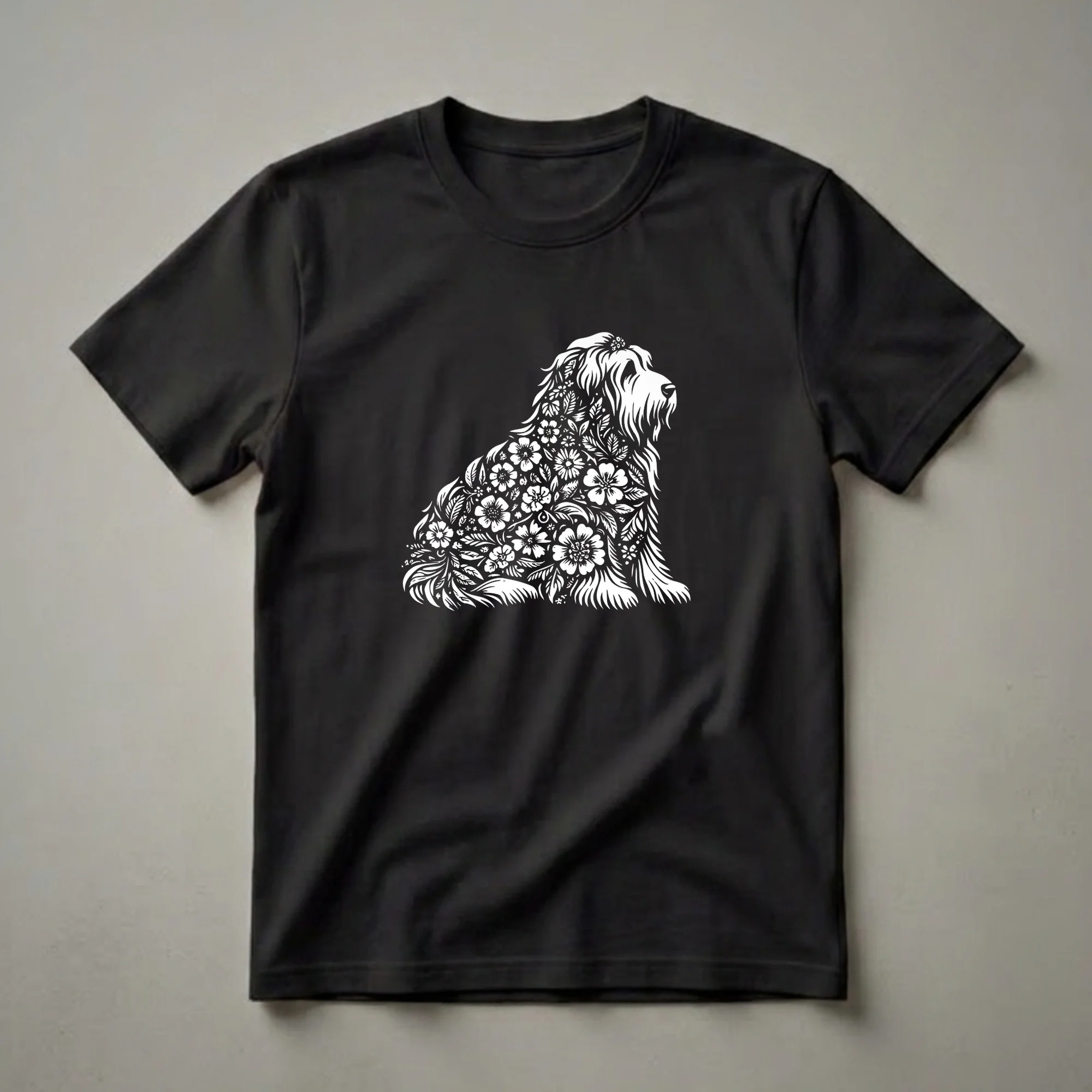 White floral illustration of a Bearded Collie dog sitting, composed of flowers and leaves, on a black t-shirt.