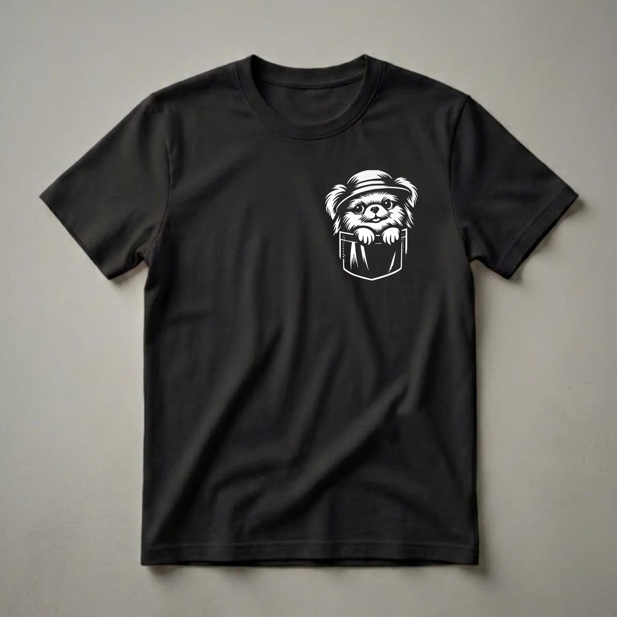 White graphic of a Japanese Chin dog wearing a hat, peeking out of a pocket, on a black t-shirt.