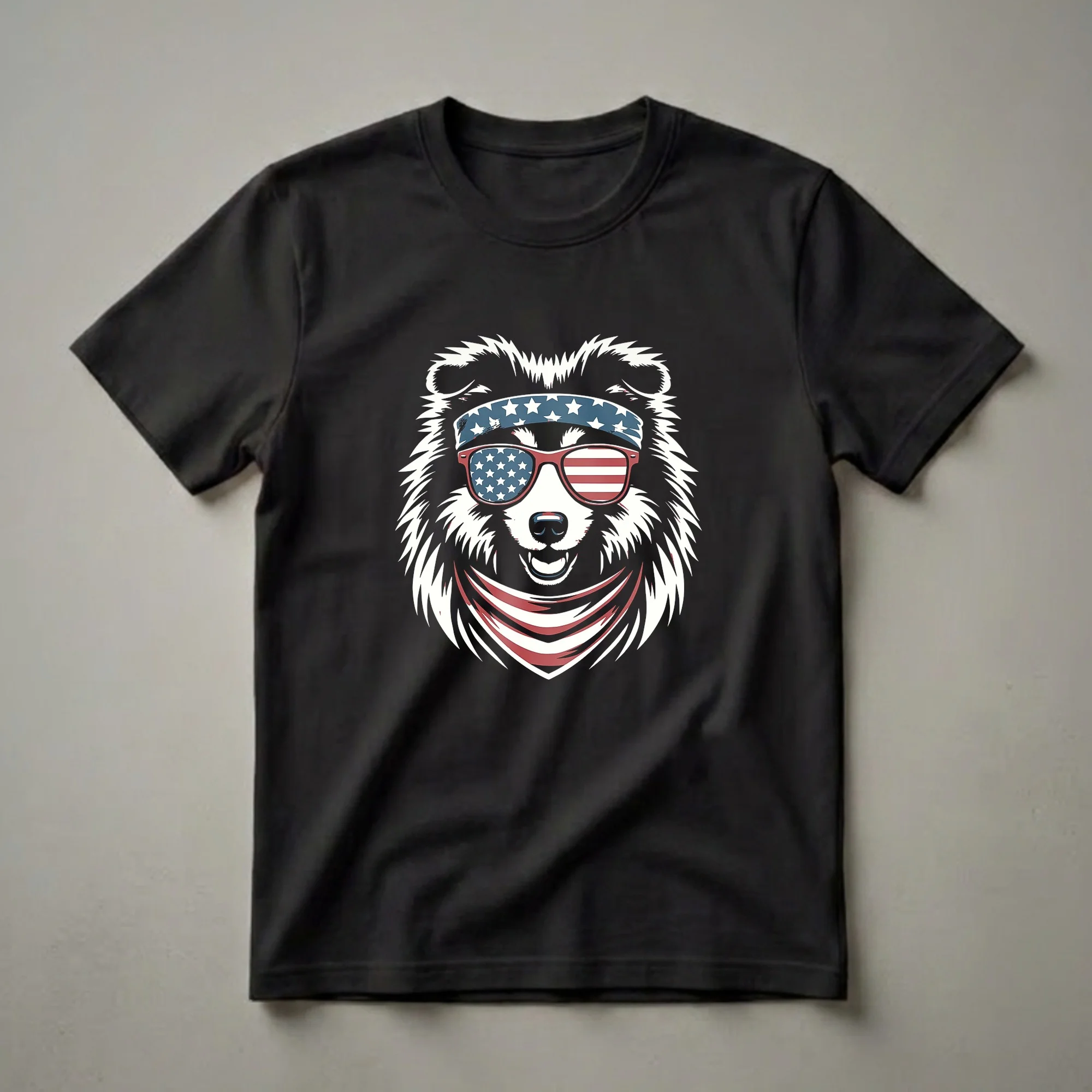 Black t-shirt featuring a graphic of a Shetland Sheepdog wearing a blue bandana with white stars, red-framed sunglasses with American flag lenses, and a red and white striped bandana around its neck.