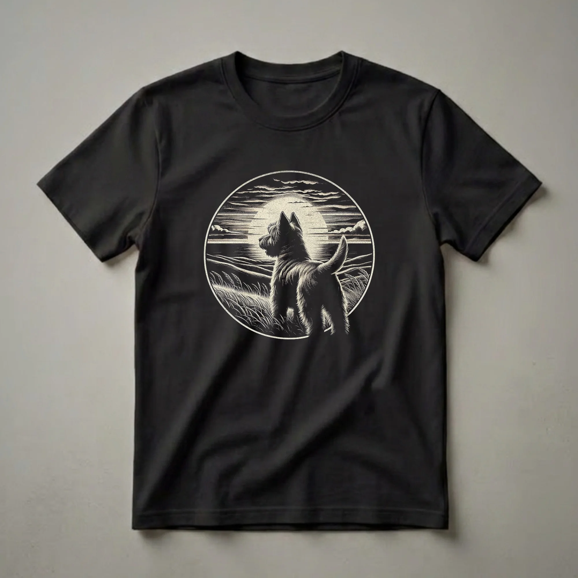 Black and white graphic t-shirt featuring a vintage woodcut illustration of a Cairn Terrier dog standing in tall grass, looking at a retro sunset scene with rolling hills and clouds.