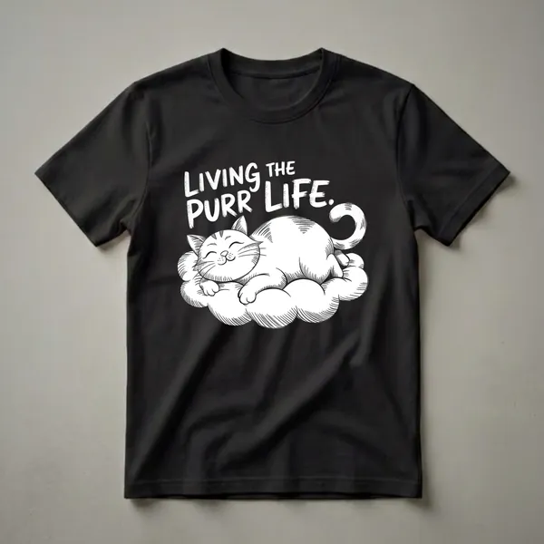 White graphic t-shirt featuring a black line drawing of a sleeping cat on a cloud with the text 'LIVING THE PURR LIFE.' in distressed white lettering.