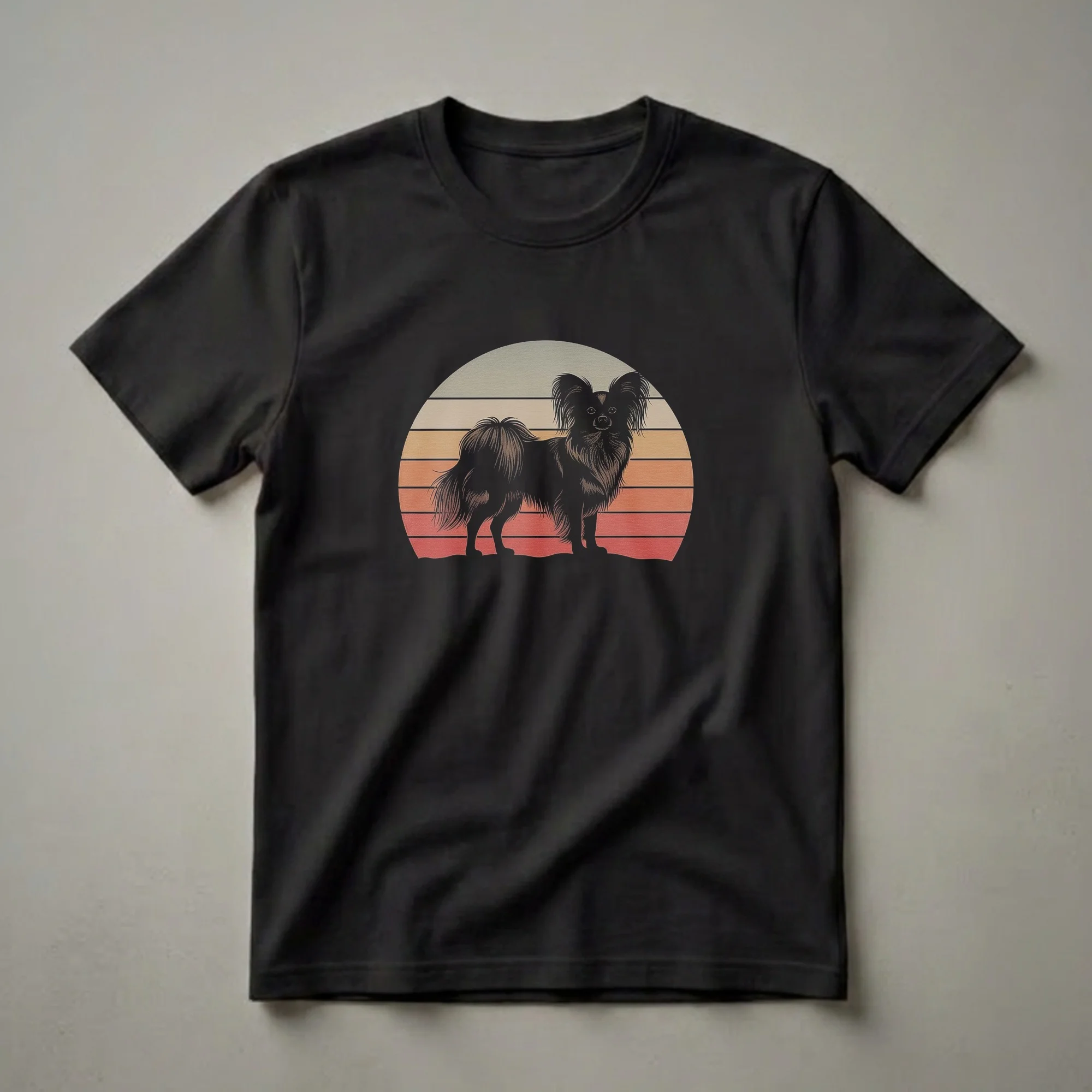 Black Papillon dog silhouette against a vintage sunset with horizontal stripes in orange, yellow, and grey, printed on a black t-shirt.