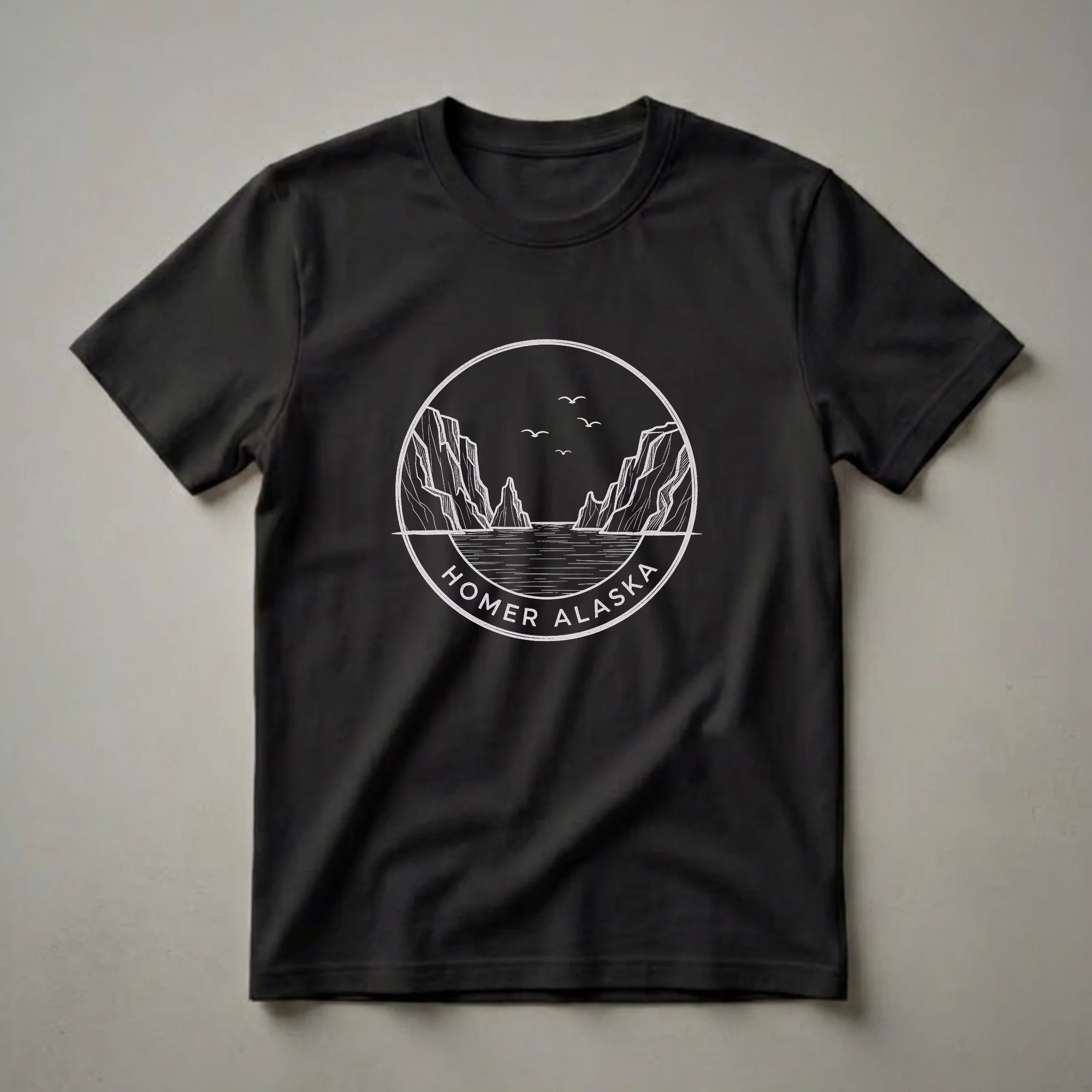 Black t-shirt featuring a vintage white sketch art design of a coastal landscape in Homer, Alaska, with rocky cliffs, water, and flying birds within a circular emblem.