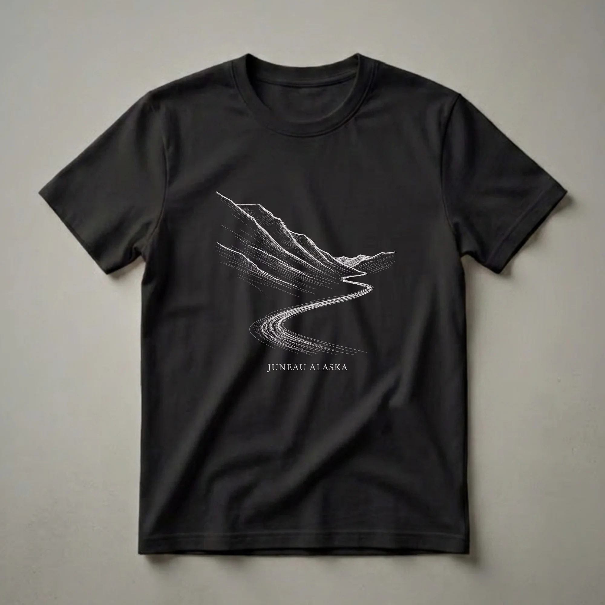 Black t-shirt with a white sketch art design of a winding road through mountains, with 'JUNEAU ALASKA' text below.