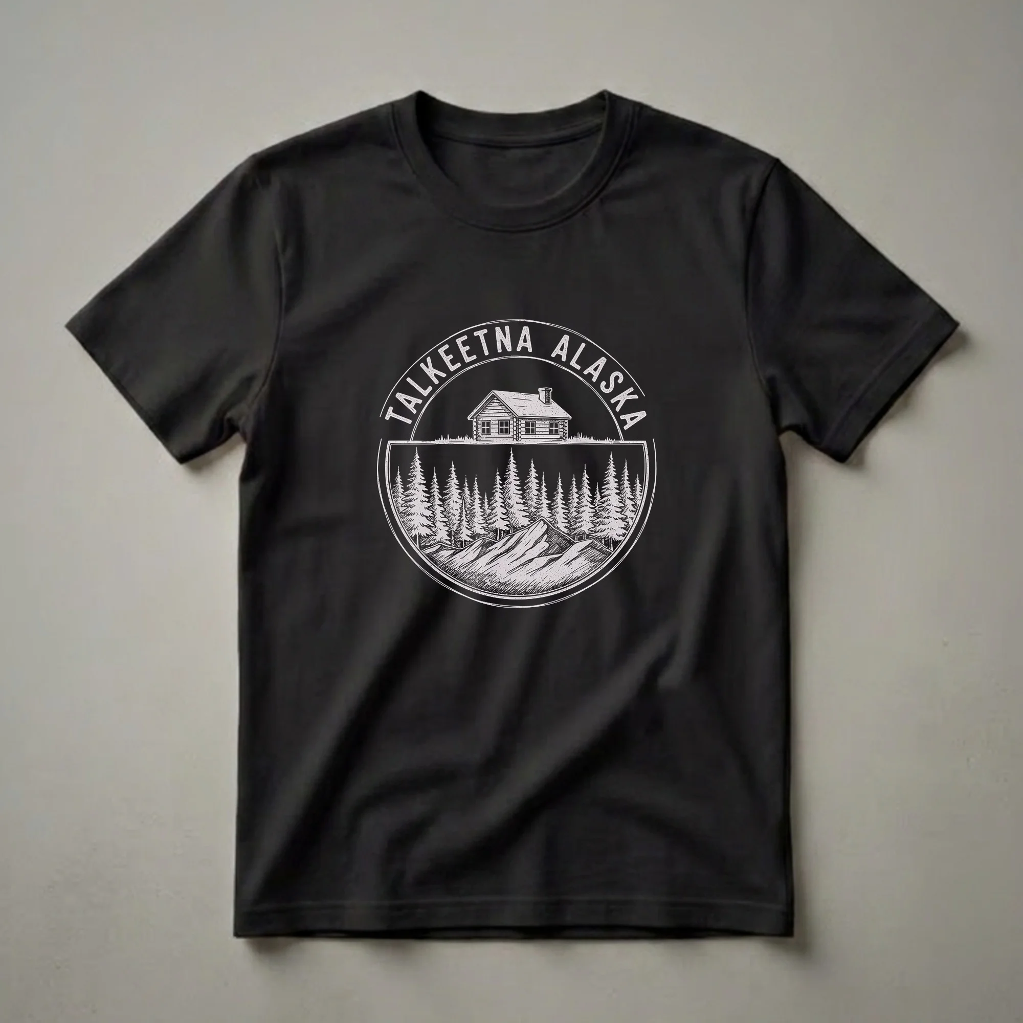 Black t-shirt featuring a vintage sketch art design of a log cabin, pine trees, and mountains, with 'Talkeetna Alaska' text in a circular emblem.