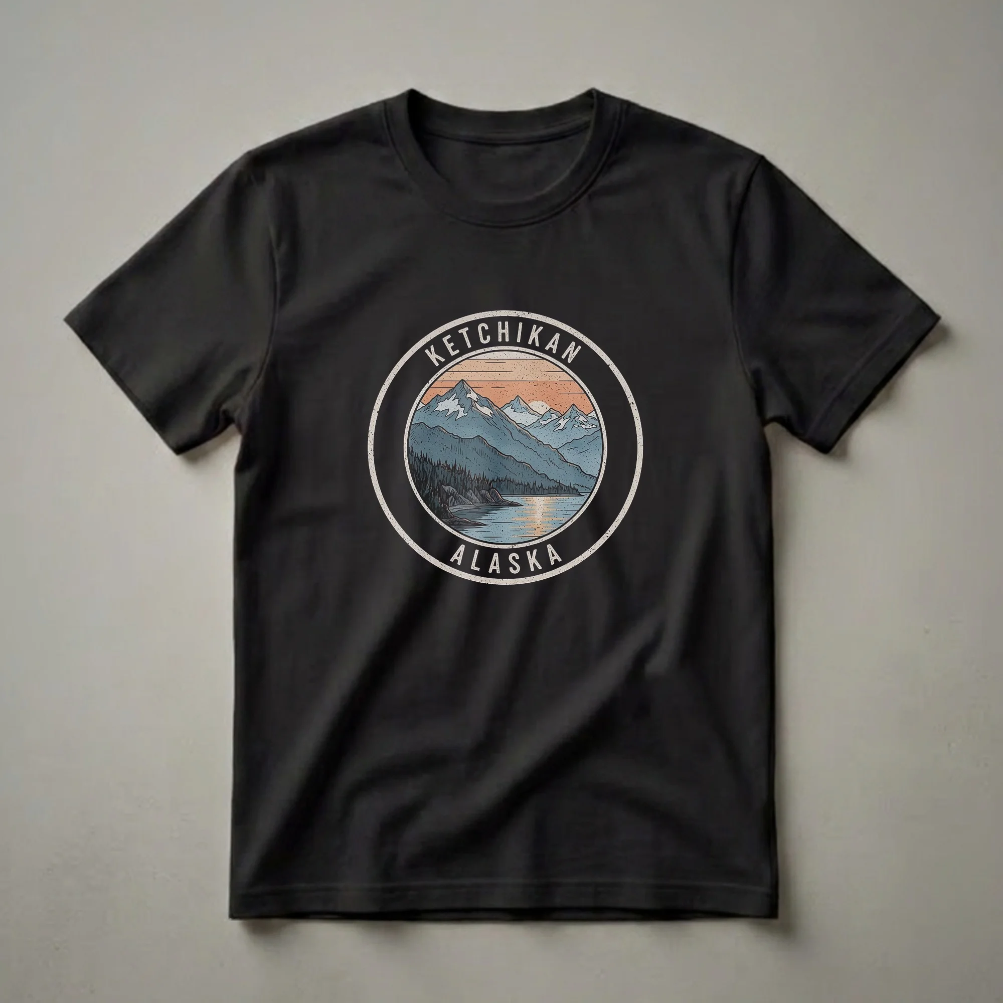 Black t-shirt with a circular graphic depicting a retro sunset over mountains, a lake, and a forest, with 'Ketchikan Alaska' text.