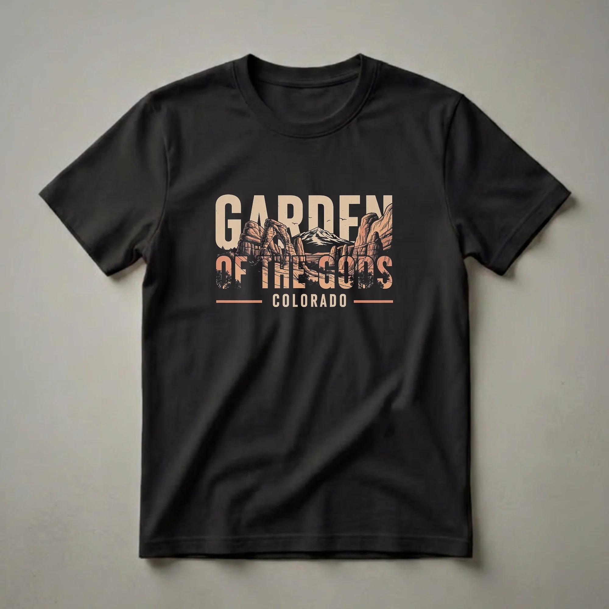 Black t-shirt with a retro graphic design of Garden of the Gods rock formations in Colorado, featuring sandstone spires and mountains.
