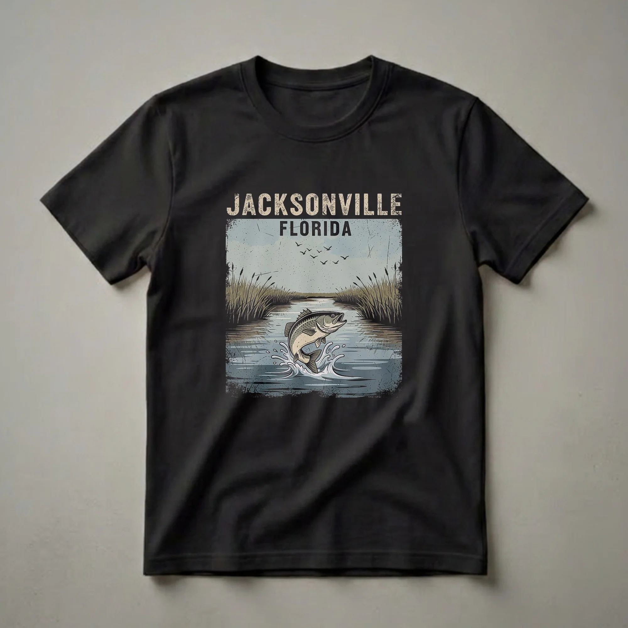A graphic t-shirt featuring a retro design of a largemouth bass leaping from water with reeds and birds in the background, representing Jacksonville, Florida.