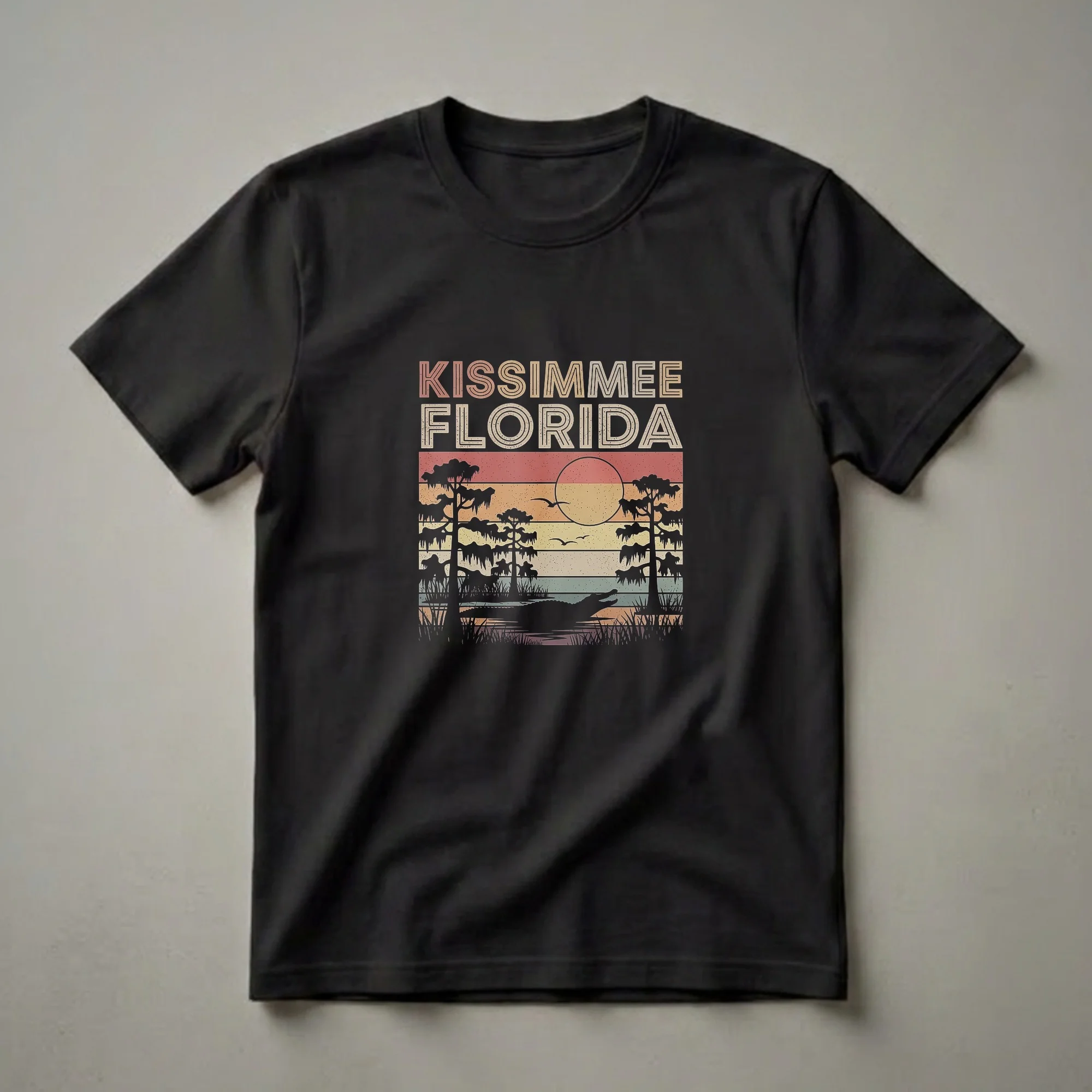 Black graphic t-shirt featuring a retro sunset scene of Kissimmee, Florida, with cypress trees, an alligator in the water, and birds flying.
