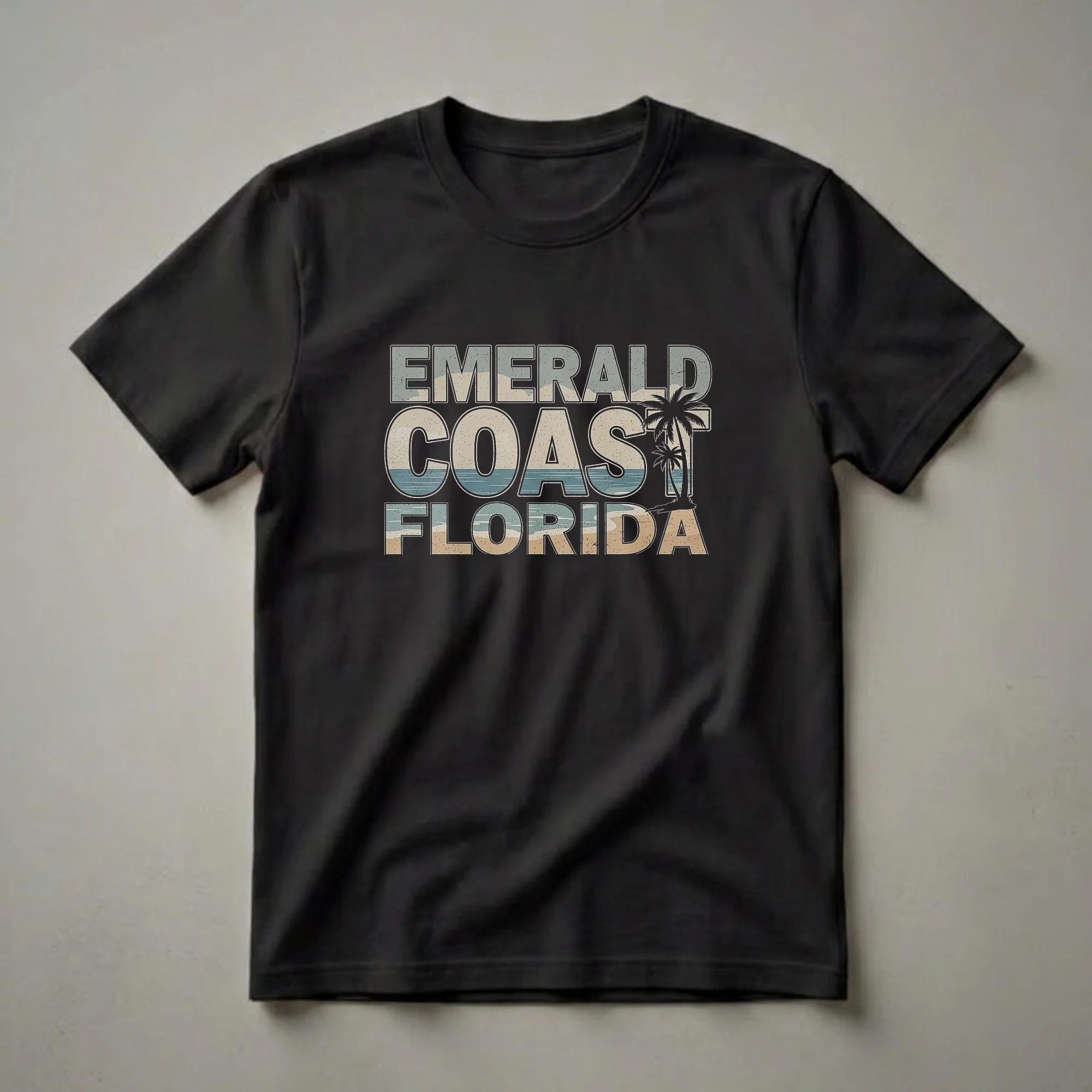 Black t-shirt with retro graphic text 'EMERALD COAST FLORIDA' featuring a beach scene with sand, ocean waves, and palm trees.