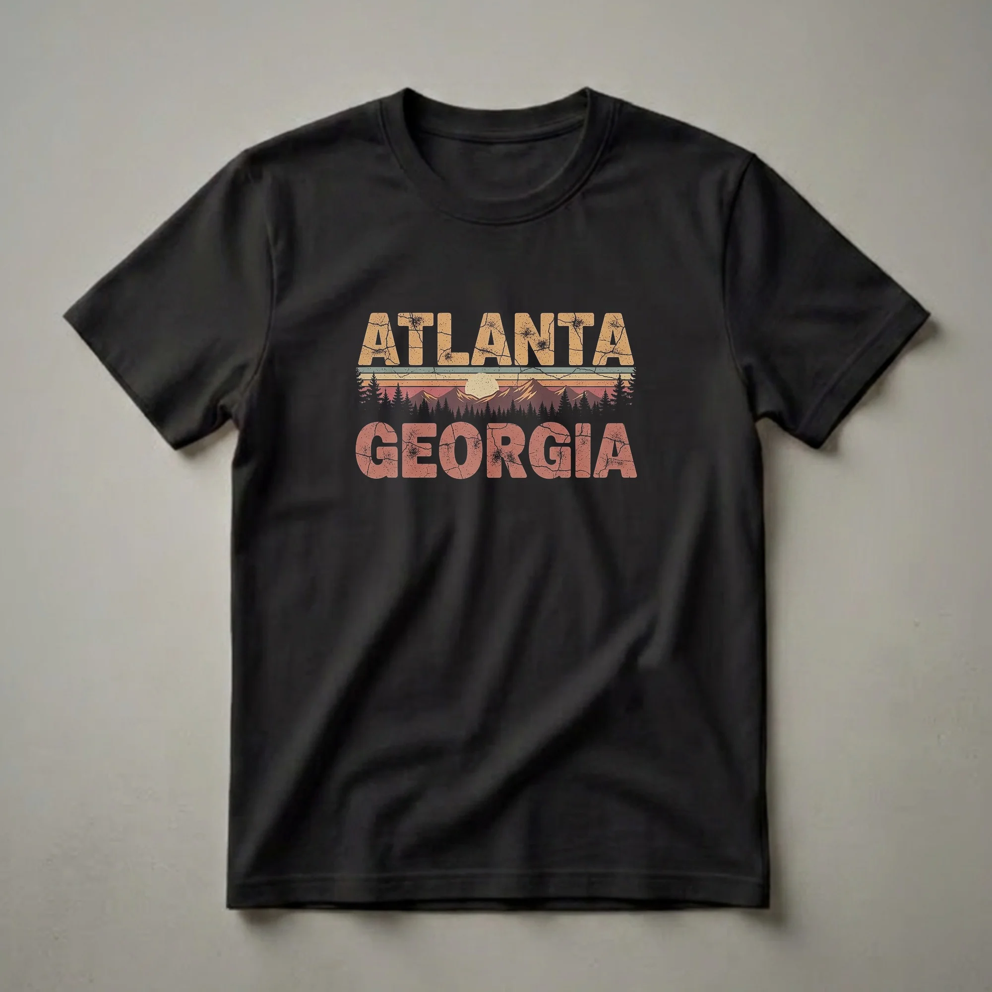 Black t-shirt with a retro graphic design featuring the words 'ATLANTA GEORGIA' in distressed fonts, set against a vintage sunset landscape with mountains and pine trees.
